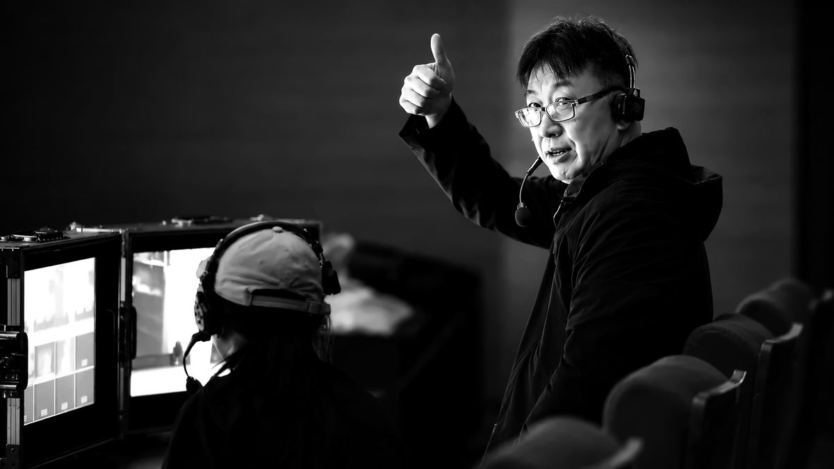 Weiping Ji with headset at the directing desk, giving a thumbs-up