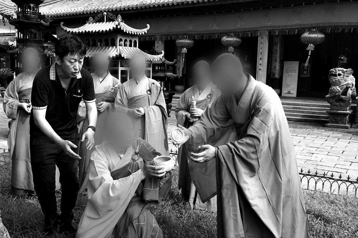 Weiping Ji explains a scene to monks in a temple courtyard