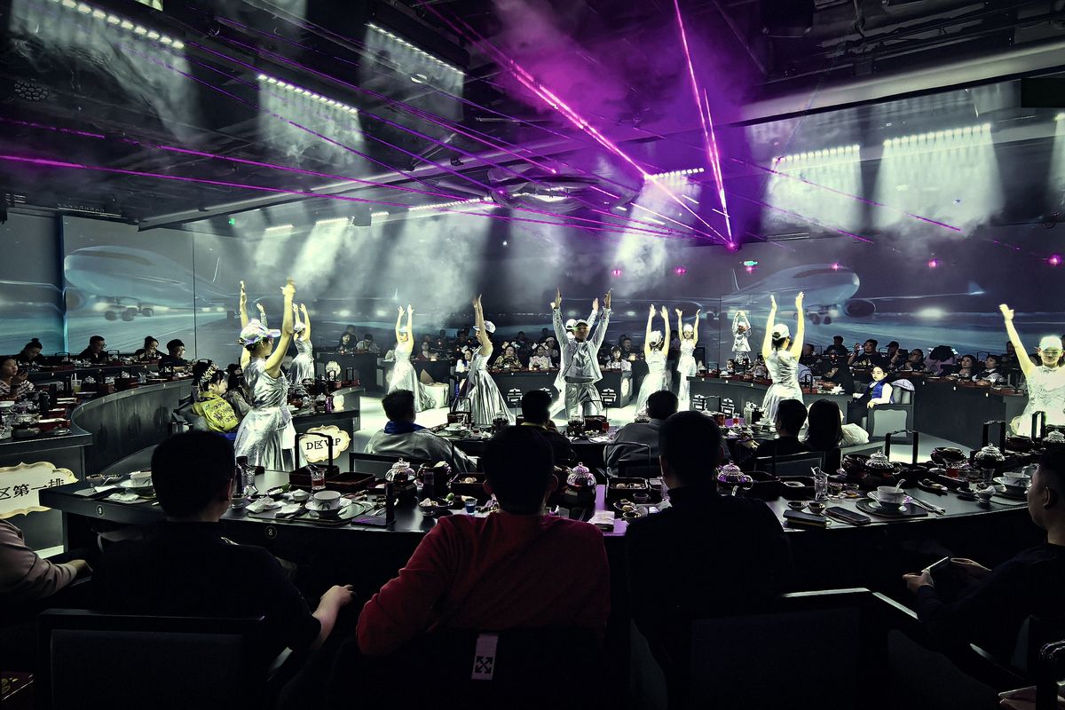 Act VI, Vitality: dancers in silver under purple lasers, the full banquet hall around them